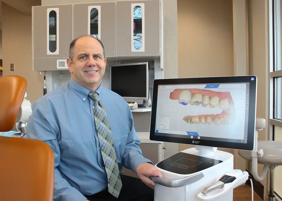 Dr. Slaman seated beside a screen showing a digital scan of a patient's teeth.